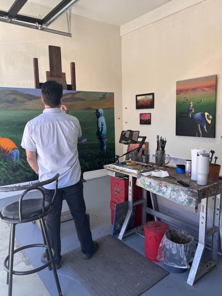 An artist paints scenes of farmers and agriculture inside a gallery store, photo ©Kate Dana