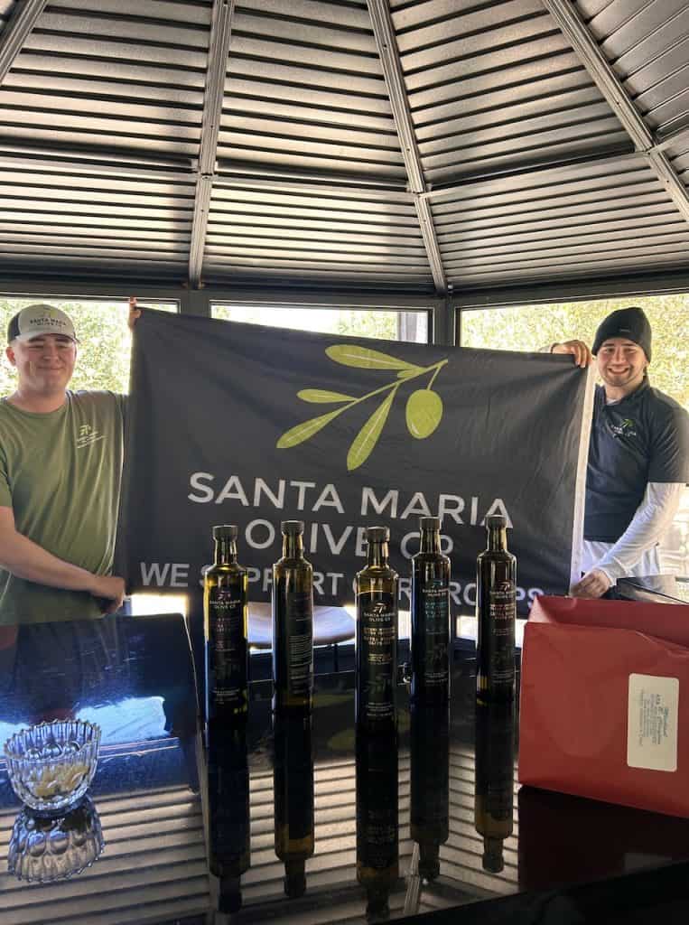 Two people hold up a large banner for the Santa Maria Olive Company, photo ©Kate Dana