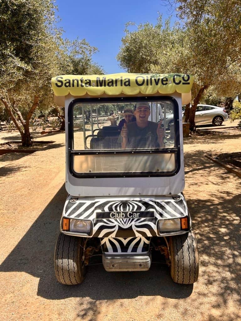 A person sits ready to take visitors on a golf car tour of the Santa Maria Olive Company, photo ©Kate Dana