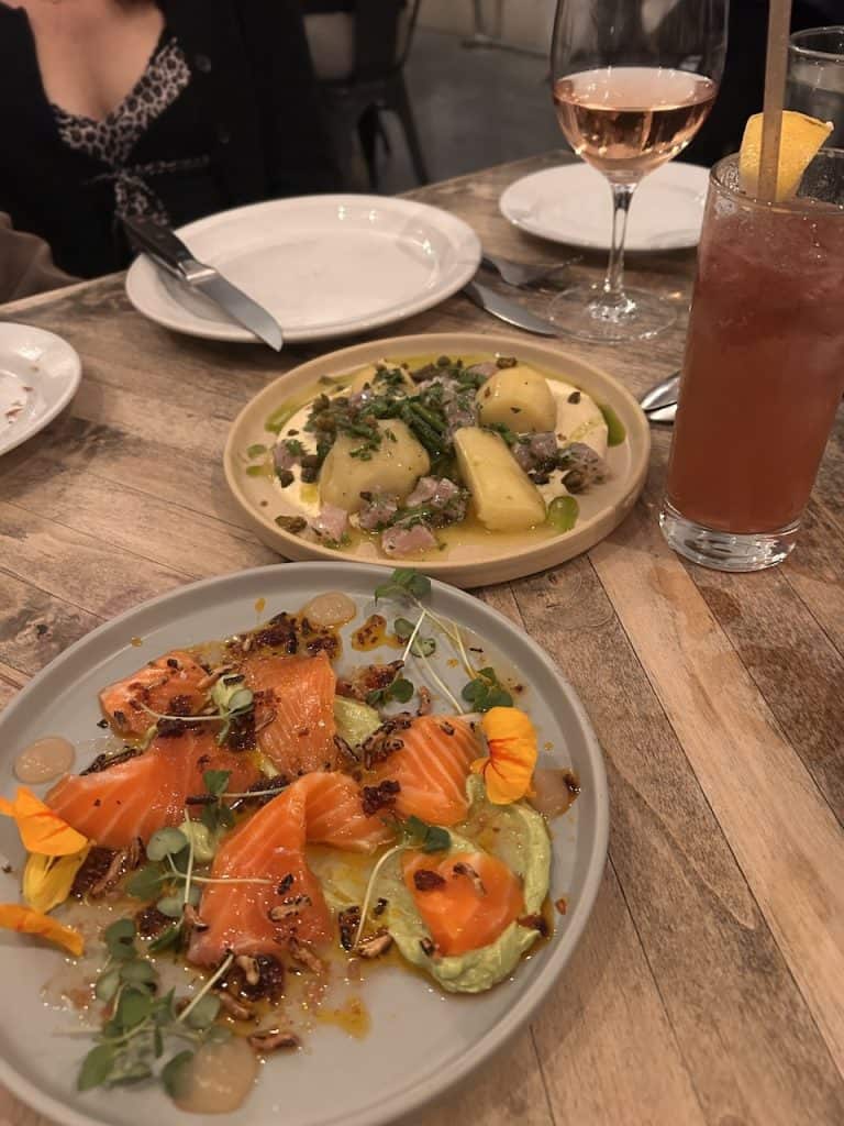 A wooden tabletop with an impressive spread of salmon and tuna tapas plates, photo © Kate Dana