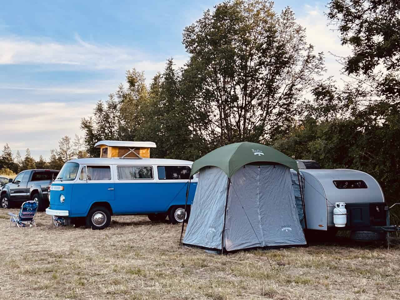 A VW Camper bus, a tent, and a small trailer on a field campground, photo ©Kate Dana