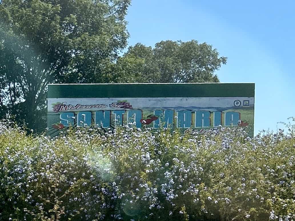 A colorful handpainted sign reading "Santa Maria" in a field of grass along highway 101 in California photo ©Kate Dana